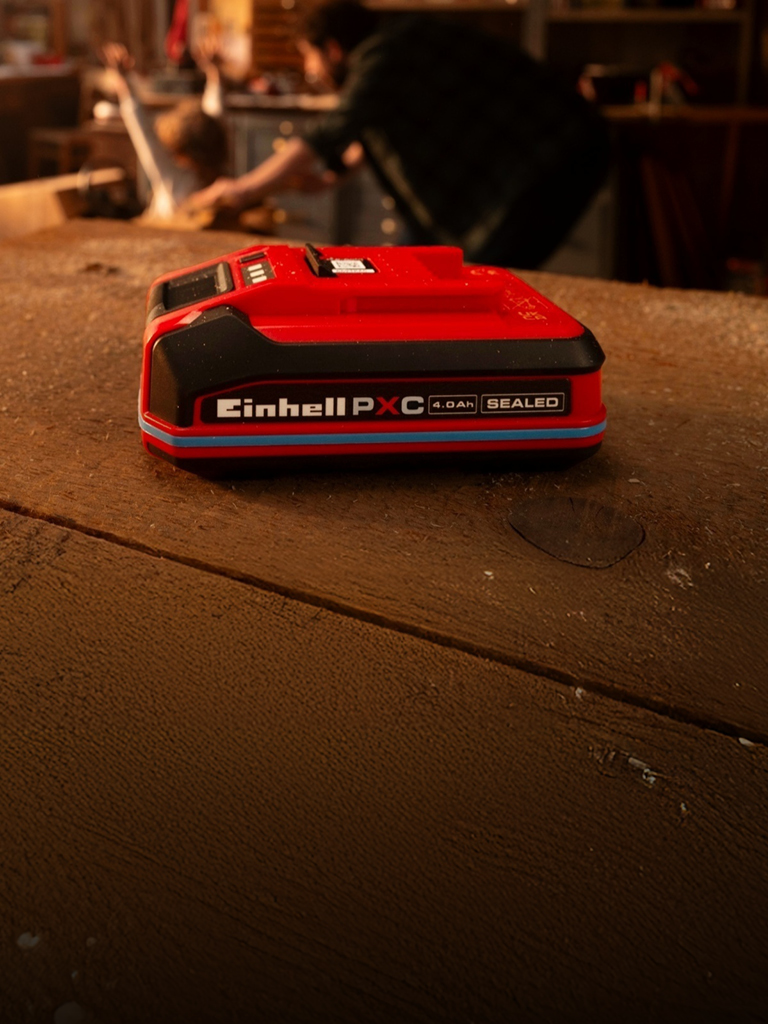 Einhell Power X-Change 4.0 Ah SEALED accu op een houten werkbank, met blauwe streep en zichtbaar label.