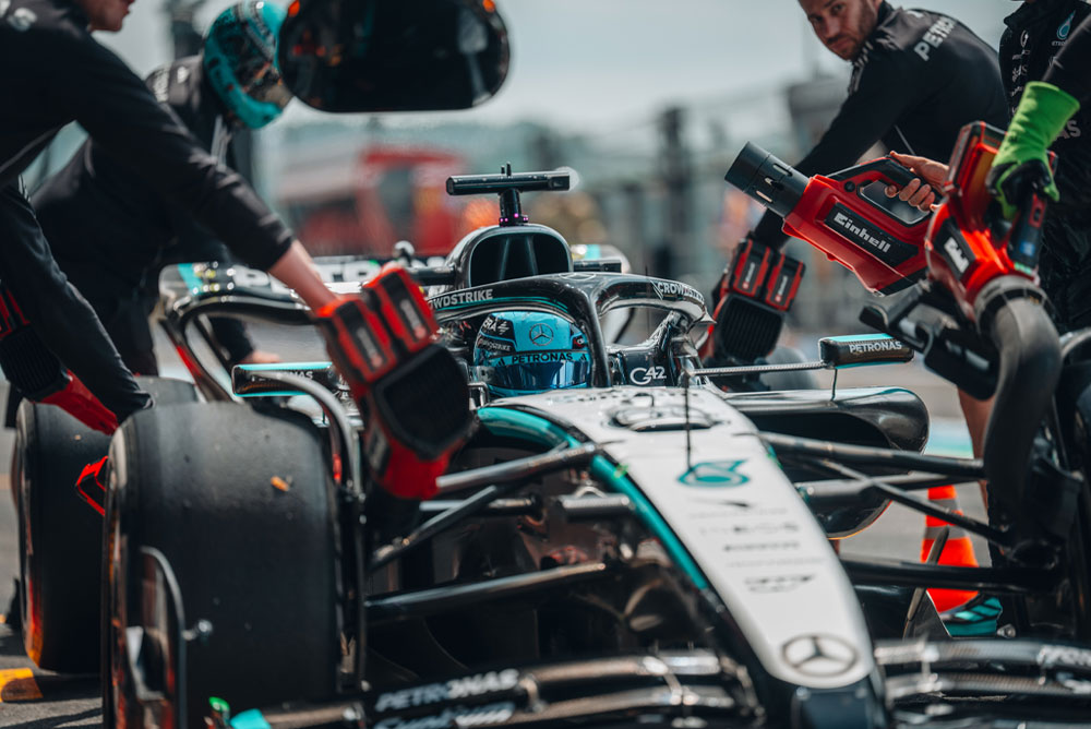Een Mercedes-AMG PETRONAS Formula One-auto tijdens een pitstop. Teamleden gebruiken snoerloze blazers van Einhell om voertuigonderdelen te koelen. Het team is gefocust en werkt nauwkeurig.