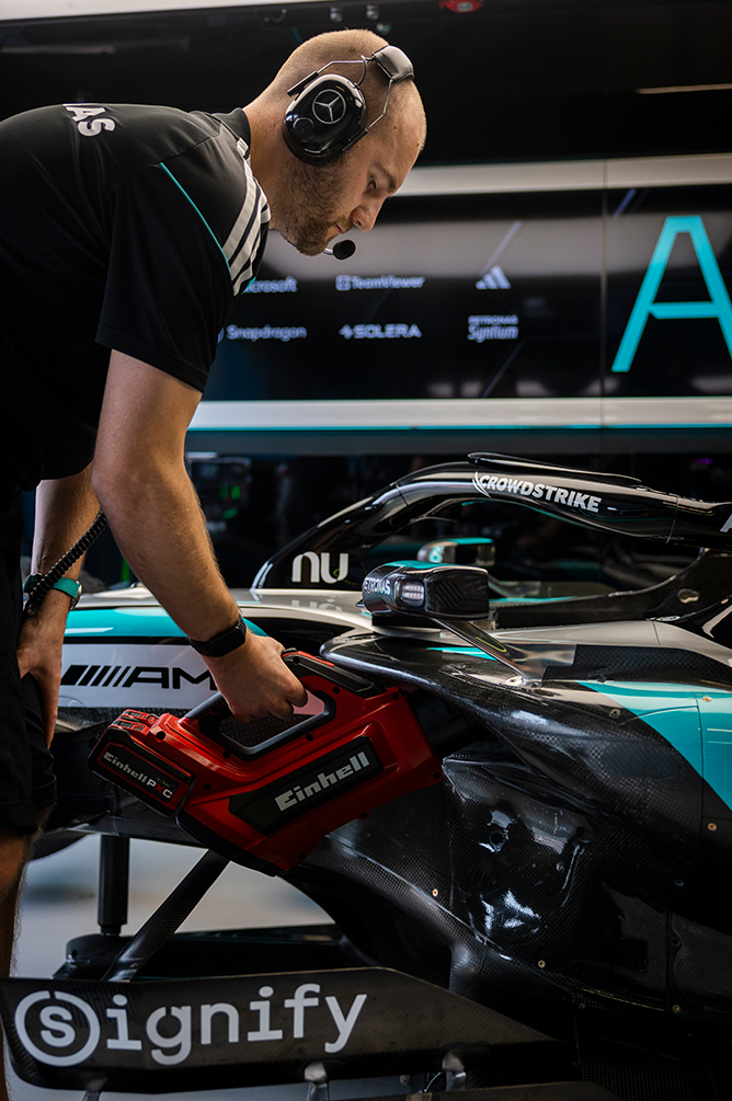 Formule 1-monteur werkt aan een raceauto in de garage met elektrisch gereedschap.