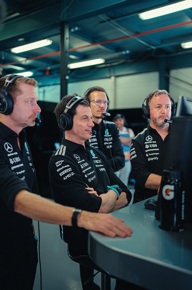 Formule 1-teamleden met headsets volgen de race vanaf de pitmuur