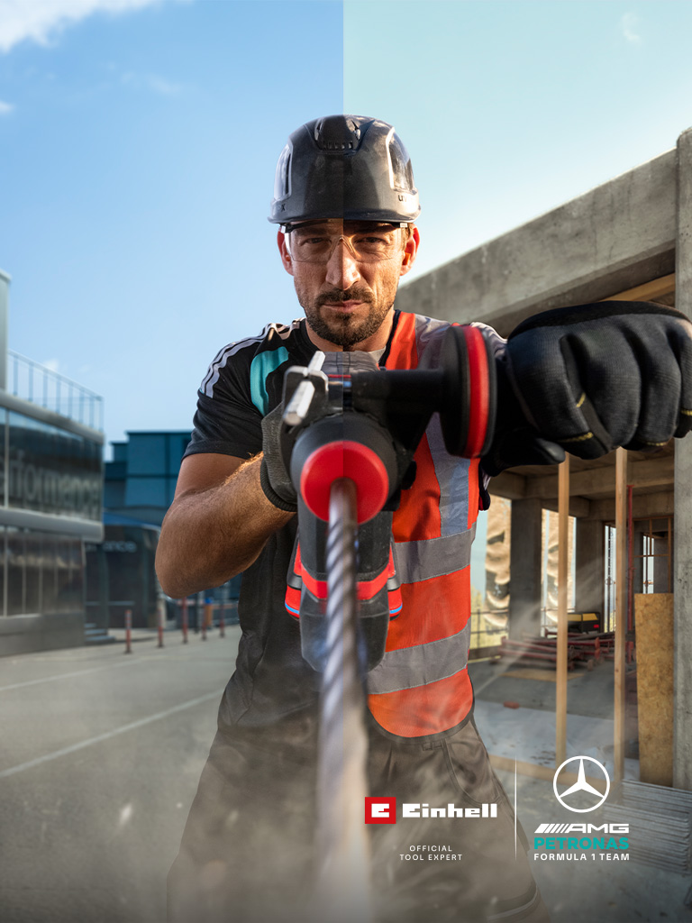 Een monteur in beschermende kleding die met elektrisch gereedschap aan het boren is op een bouwplaats.