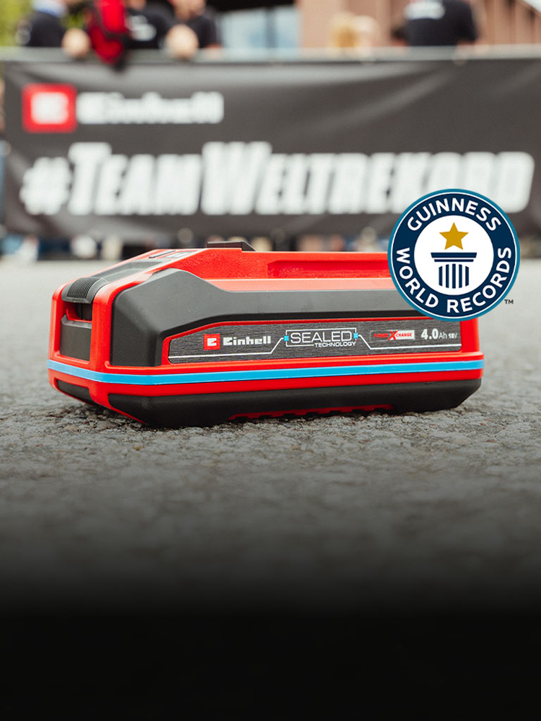 Einhell Power X-Change 4.0 Ah SEALED Accu ligt op het asfalt, met rechts het logo ‘Recordhouder’ van Guinness World Records.