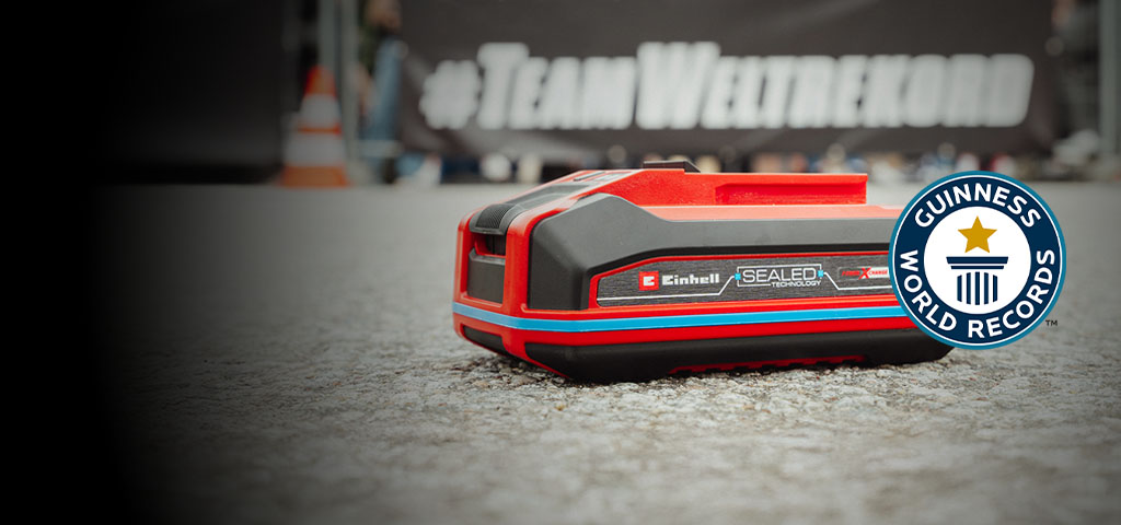 Einhell Power X-Change 4.0 Ah SEALED Accu ligt op het asfalt, met rechts het logo ‘Recordhouder’ van Guinness World Records.