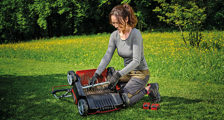 Een vrouw maakt de mesrol van een verticuteermachine schoon.